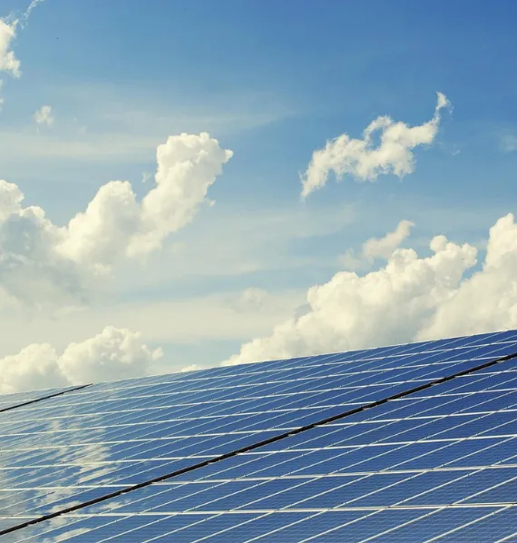 Solar panel array angled toward blue sky with white clouds