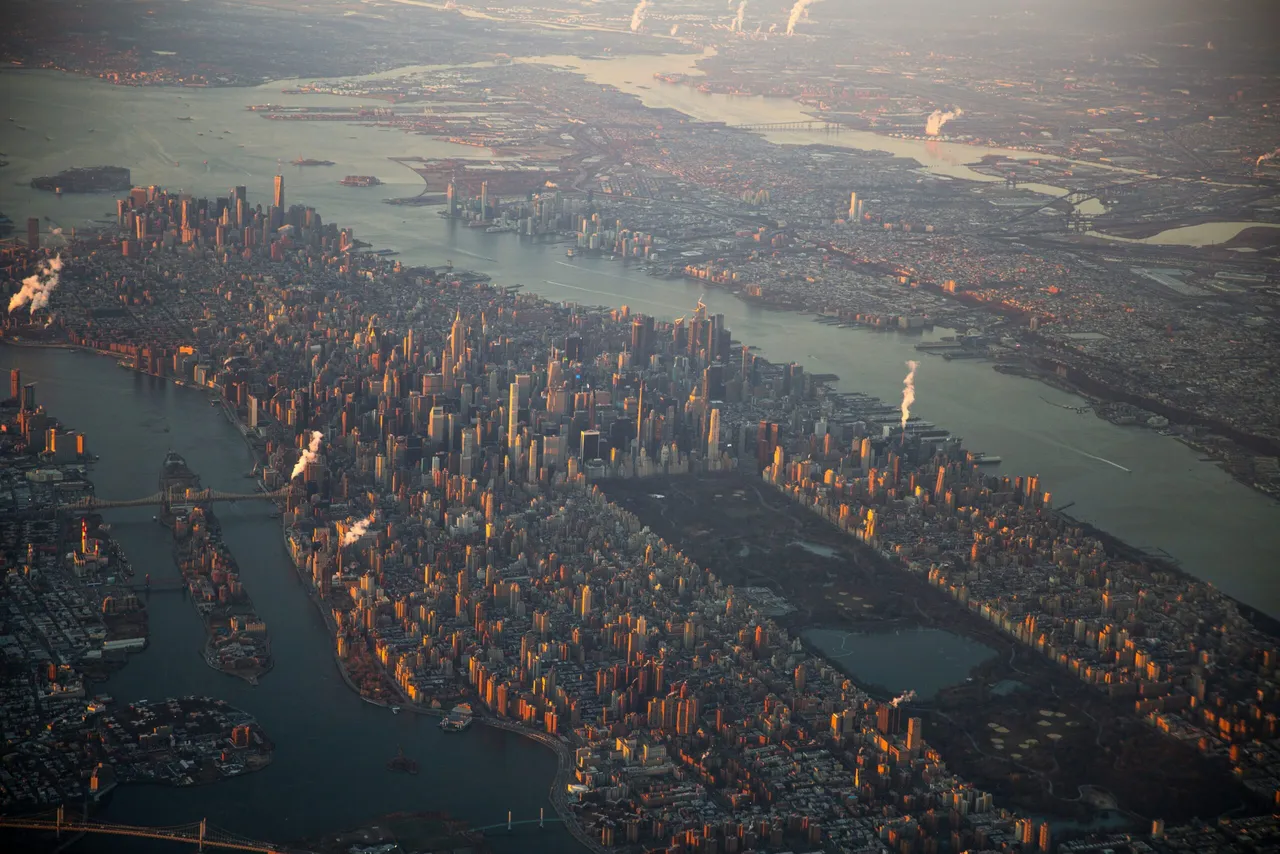 Aerial view of a major city with tall buildings, waterways and bridges at sunset