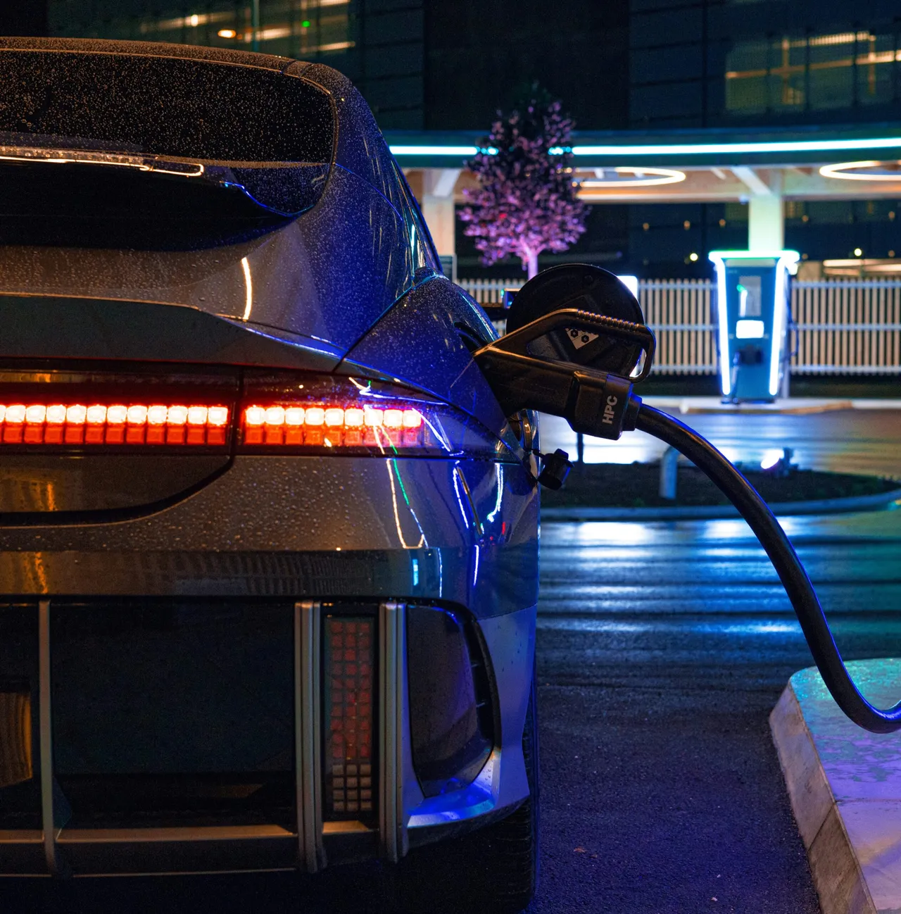 Electric vehicle plugged into charging station at night in urban setting