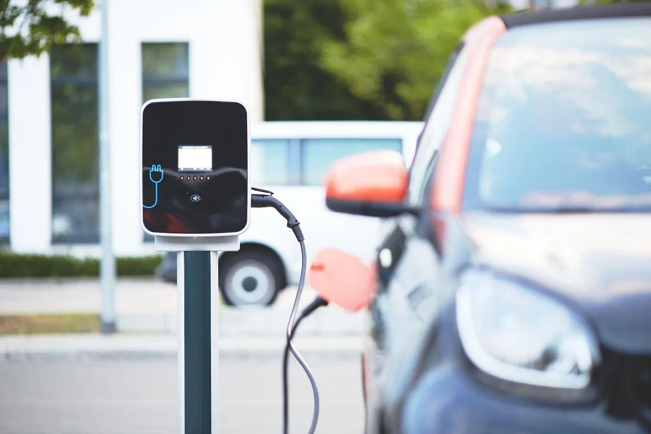 Electric vehicle charging point with cable connected and cars parked nearby