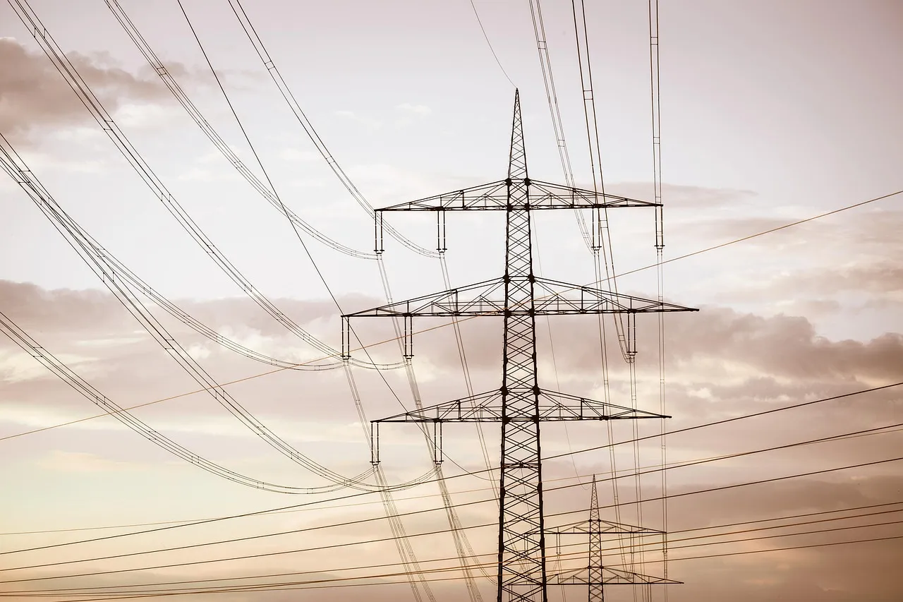 High-voltage electricity pylon with multiple crossarms and power lines against a cloudy sky