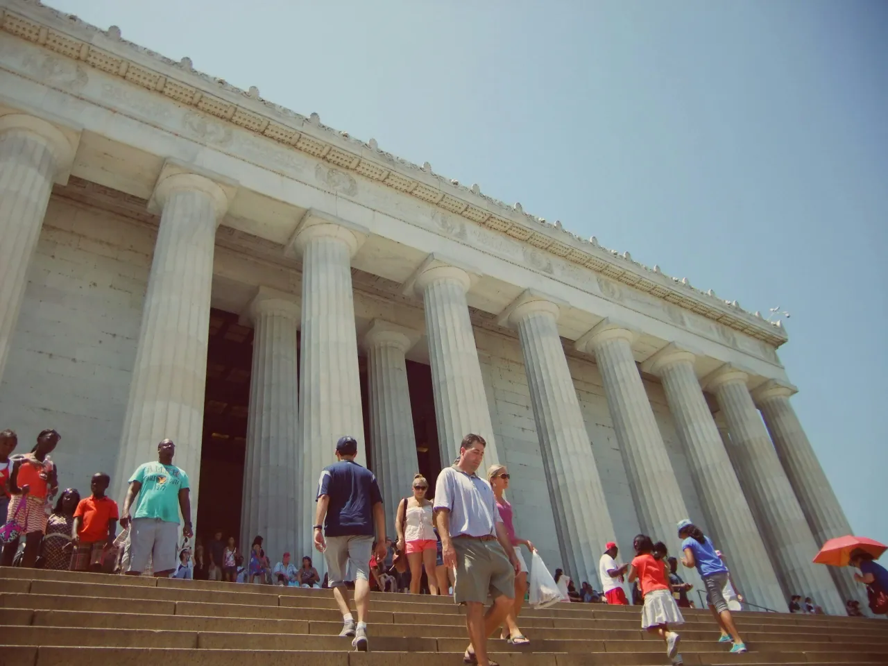 Visitors walking on steps in front of a large neoclassical building with tall white columns