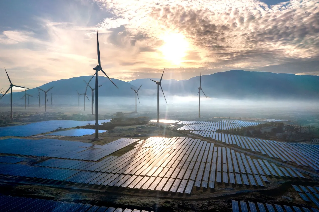 A solar array and wind turbines at sunset