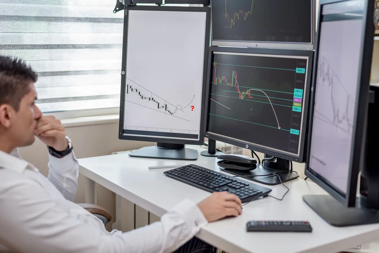 A trader working across four monitors