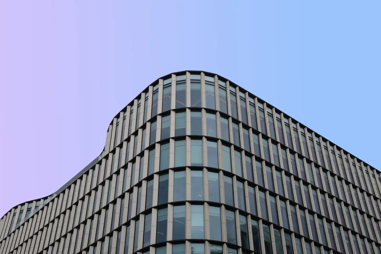 Curved glass and steel office building against a pale sky